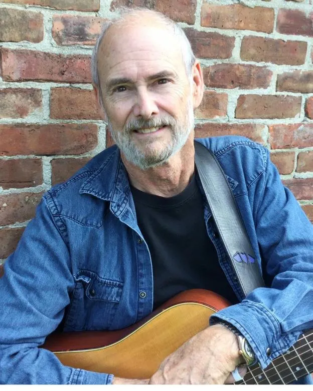 John Dillon, songwriter and recovery coach, holding a guitar